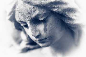 Death concept. Close Up of ancient stone statue of crying angel with tears in face as symbol of end...