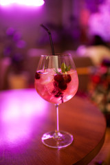 alcoholic cocktail with berries and melissa on the table in the bar