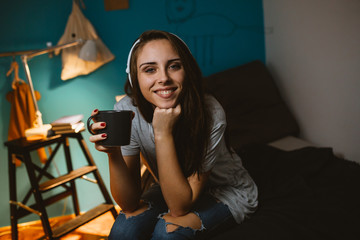 young woman in her room listening music on headphones