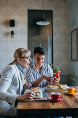 women having lunch at restaurant. using mobile phone