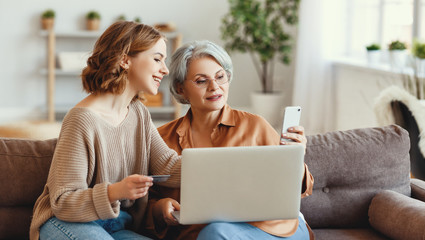 Young woman with mother shopping online at home. - obrazy, fototapety, plakaty