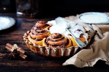 Cinnamon Rolls Baked in Ceramic Mold with Cream Cheese Icing on a Dark Wooden Background