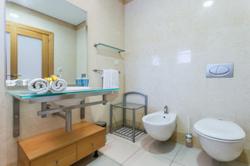 Modern bathroom with toilet and washbasin, unique design. With white towels.