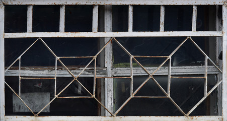 Old wooden window behind a metal grate. Vintage texture