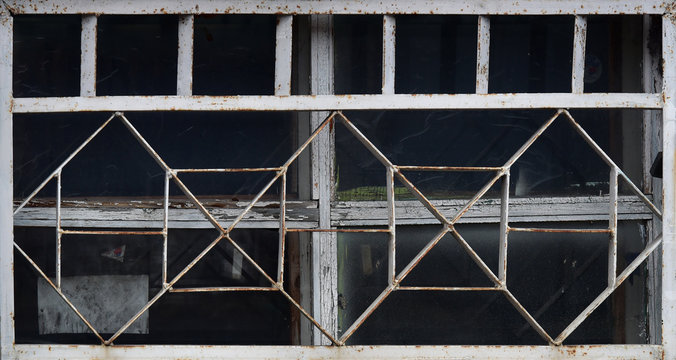 Old wooden window behind a metal grate. Vintage texture