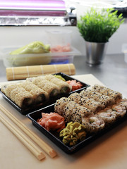 There are sushi takeaway boxes on the table at the sushi bar