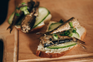 Sandwich with sprats on wooden table. Top view.