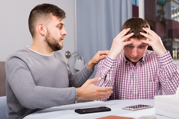 Fototapeta premium Friend soothing upset man at home table
