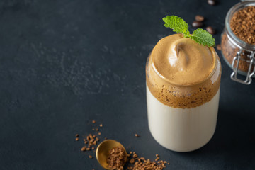 Dalgona frothy coffee in glass on black. Trend korean drink latte espresso with coffee foam.