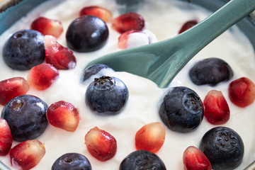 Bowl of yogurt, fresh blueberries, and seeds of pomegranate . Healthy breakfast, close up