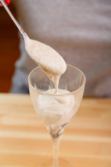 A female hand holds a spoon and puts the crushed mass into a smoothie glass.