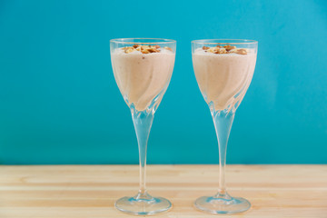ice cream smoothie with banana and chocolate sprinkled with nuts on a blue background.