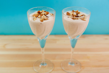 ice cream smoothie with banana and chocolate sprinkled with nuts on a blue background.