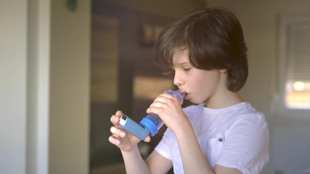 Boy using an asthma inhaler.
Close-up of boy using asthma inhaler at home.
