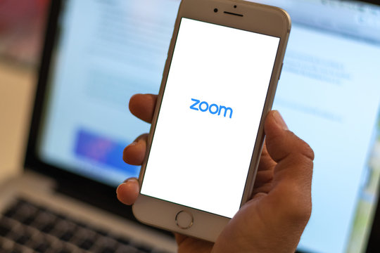 Guilherand-Granges, France - April 14, 2020. Woman holding iPhone with app  Zoom. App for video conference, social distancing and home work.