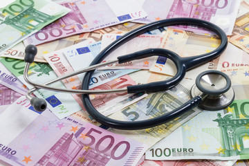 Stethoscope lying on top of various Euro banknotes. Medical cost, insurance, wealth, health, education concept..