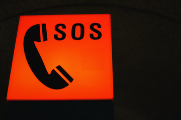 A luminous orange signal with an emergency phone and SOS acronym.