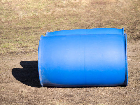 Two blue plastic barrels lie on the ground. The concept of safe storage of liquids