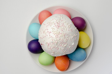 Kulich Easter cake with colored eggs with white glaze on white background
