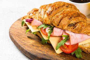 Croissant sandwich on white table.