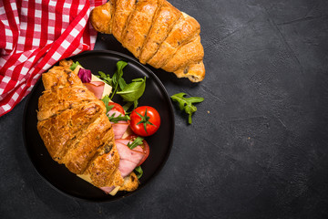 Croissant sandwich on black table.