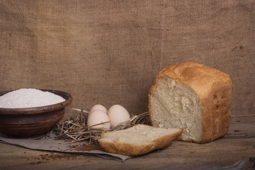 A cut piece of white bread, eggs and flour on a wooden table