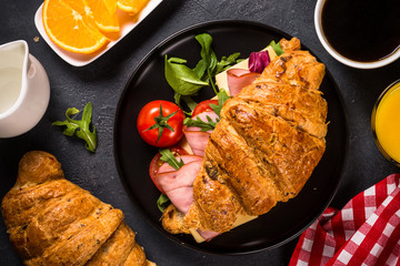 Croissant sandwich on black table.