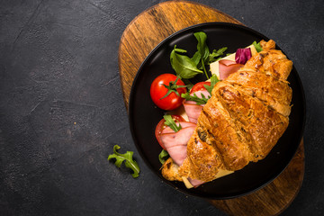 Croissant sandwich on black table.