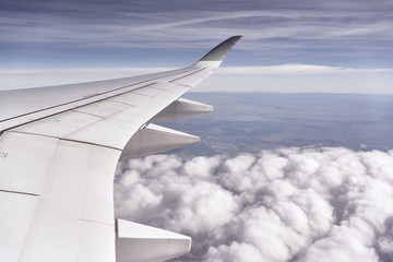 Passenger plane flying above the clouds. View from the wing of the plane.