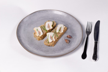 Open sandwich with fat, grain bread, scallions, garlic on gray plate on white background