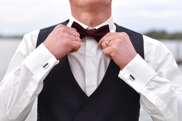 The groom is preparing for the wedding, holding hands on a butterfly on the neck