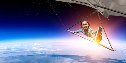Fototapeta na wymiar Young woman flying on hang glider. Mixed media