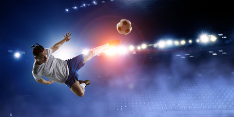 Football player on stadium jumps to kick a ball
