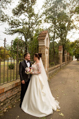 In love wedding couple posing in park near old wall