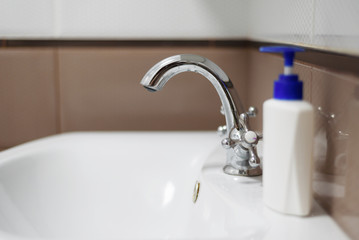 A bottle of soap on the white sink in the bathroom.