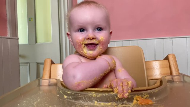 A happy young baby covered in food during baby led weaning