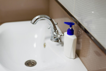 A bottle of soap on the white sink in the bathroom.