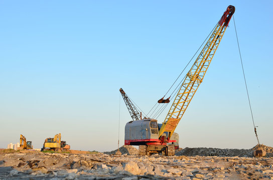 Large crawler crane or dragline excavator with a heavy metal wrecking ball on a steel cable. Wrecking balls at construction sites. Dismantling and demolition of buildings and structures