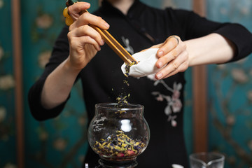  Tea ceremony. Girl pours tea leaf into a glass flask.