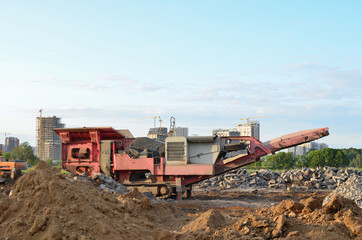 Fototapeta premium Mobile Stone Jaw crusher machine for crushing concrete into gravel and subsequent cement production. Salvaging and recycling of the demolition construction waste on landfill. Reuse concrete.