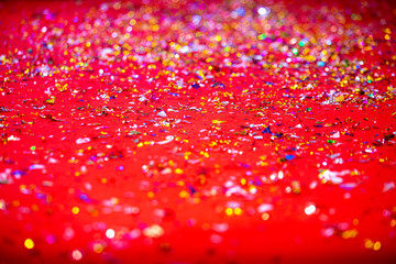 Gold or silver plastic laces cover on the red carpet. Red glitter texture abstract background.