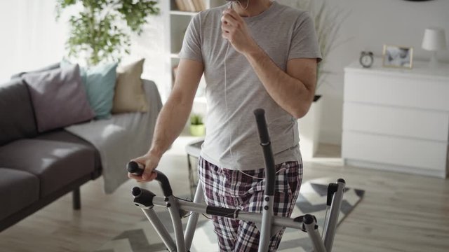 Tilt up of man exercising at home on cross trainer. Shot with RED helium camera in 8K.