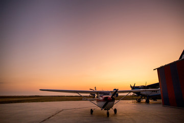 Fototapeta na wymiar Private plane on field at sunset