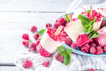 Sweet and tasty diet summer dessert. Homemade raspberry yogurt popsicle with fresh raspberries and mint. Healthy ice cream recipe. Wooden white background copy space
