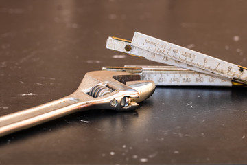 Tools for repair and building. Adjustable spanner, ruler and instruments on black wooden table with...