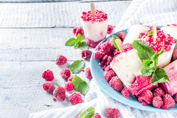 Sweet and tasty diet summer dessert. Homemade raspberry yogurt popsicle with fresh raspberries and mint. Healthy ice cream recipe. Wooden white background copy space
