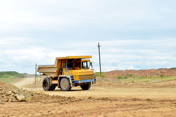 Big yellow mining truck working in the limestone open-pit. Loading and transportation of minerals in the dolomite mining quarry. Belarus, Vitebsk, in the largest dolomite deposit, quarry 