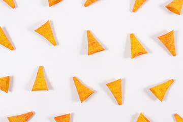 Triangular, corn tortilla chips nachos with unusual shape on bright white background. Open composition. Snack food background. Top view. Mexican food.