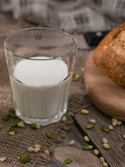 Glass of milk and scattered seeds and nuts on planked wooden table. Vertical shot from above.