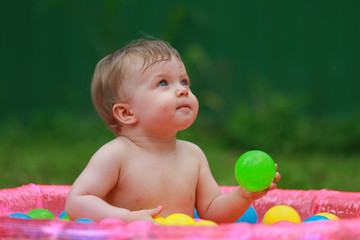 Fototapeta na wymiar The baby swims in swimmimng pool with balls. Summertime in swimming pool. 